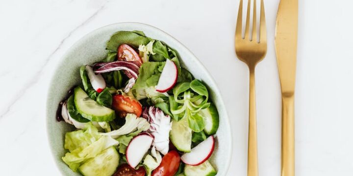 Delicious vegetable salad and golden fork and knife on table