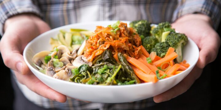 person holding plate with vegetables