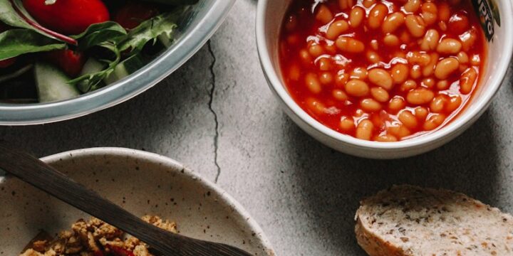 sliced bread with sliced tomatoes and green leaves on white ceramic bowl